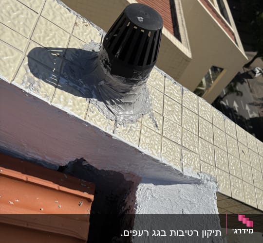 צינור פלסטיק שחור על גג מרוצף עם איטום אפור
